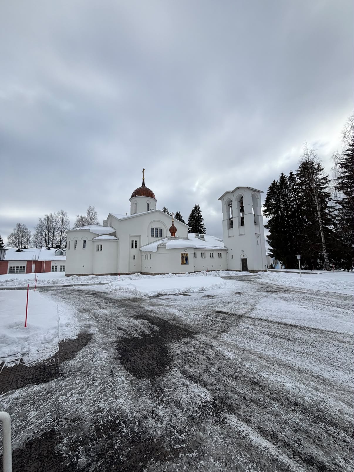 Hvit ortodoks kirke og klokketårn i vinterlandskap